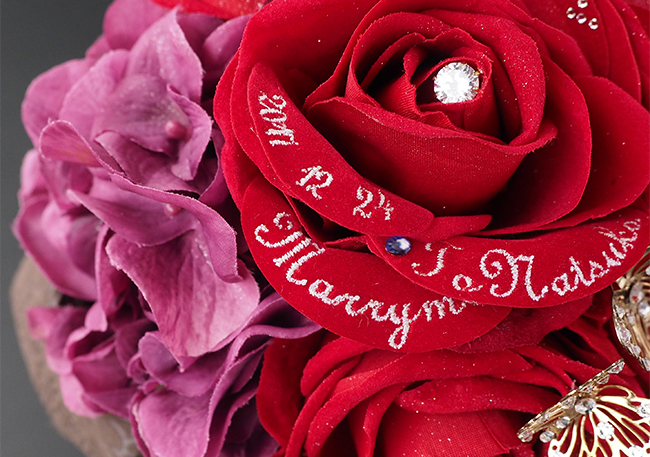赤い花びらに白い糸でメッセージを刺繍